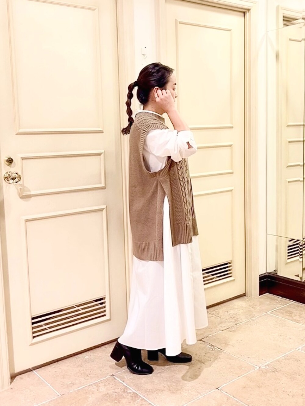 ブラウン系のベスト、ブルー系のデニムパンツ、ホワイト系のシャツワンピースを着用したレディースの秋コーディネートの2枚目の写真