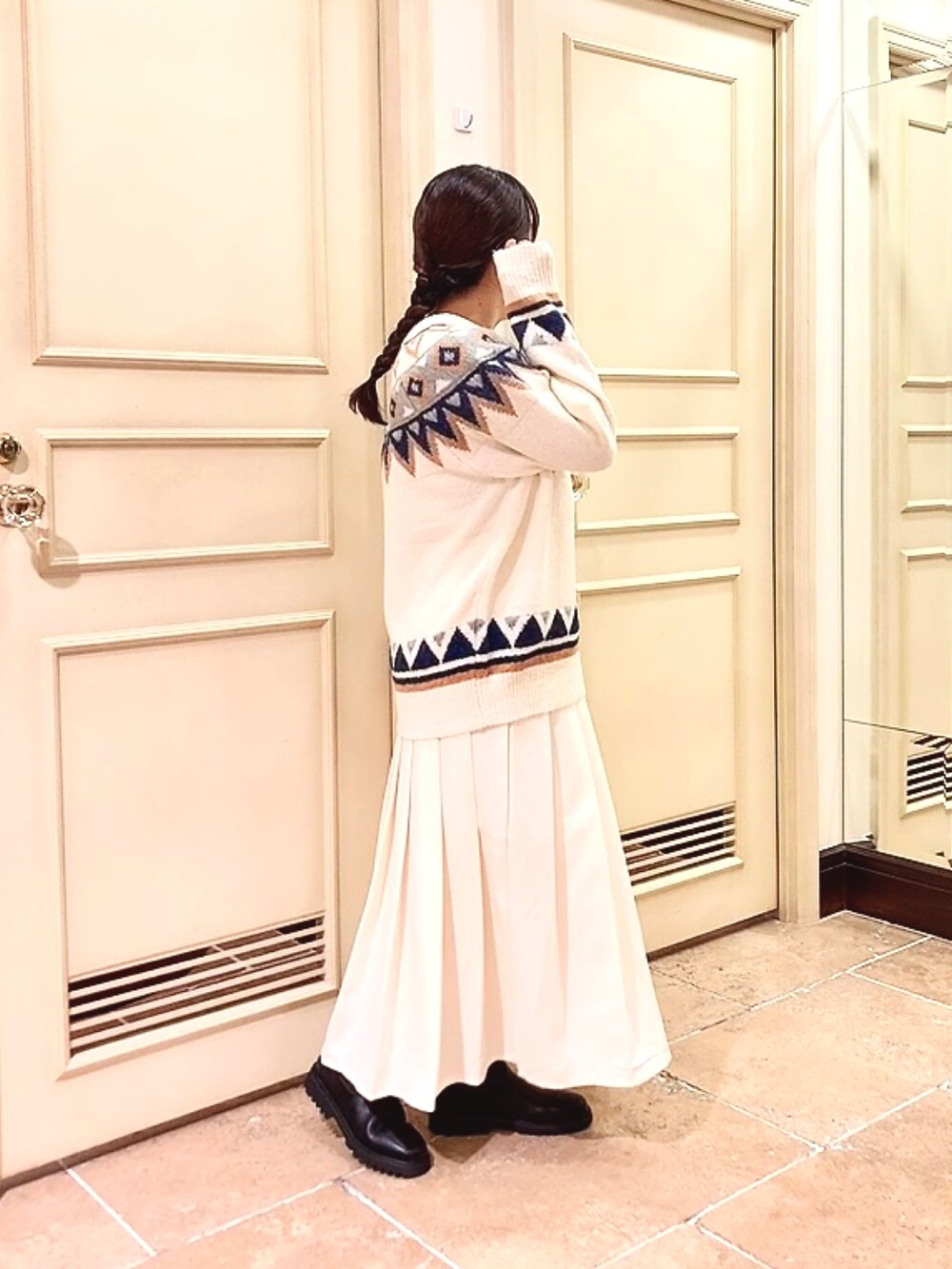 ブラック系のブーツ、ホワイト系のニット/セーター、ホワイト系のスカートを着用したレディースの冬コーディネートの2枚目の写真