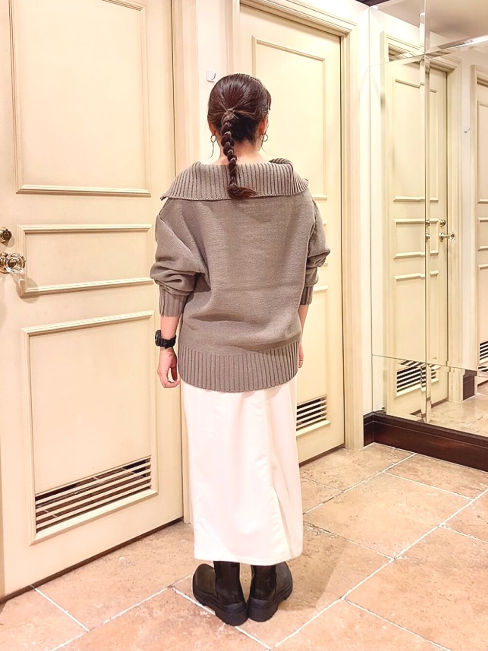 ブラック系のブーツ、ホワイト系のスカート、ブラウン系のニット/セーターを着用したレディースの秋コーディネートの2枚目の写真