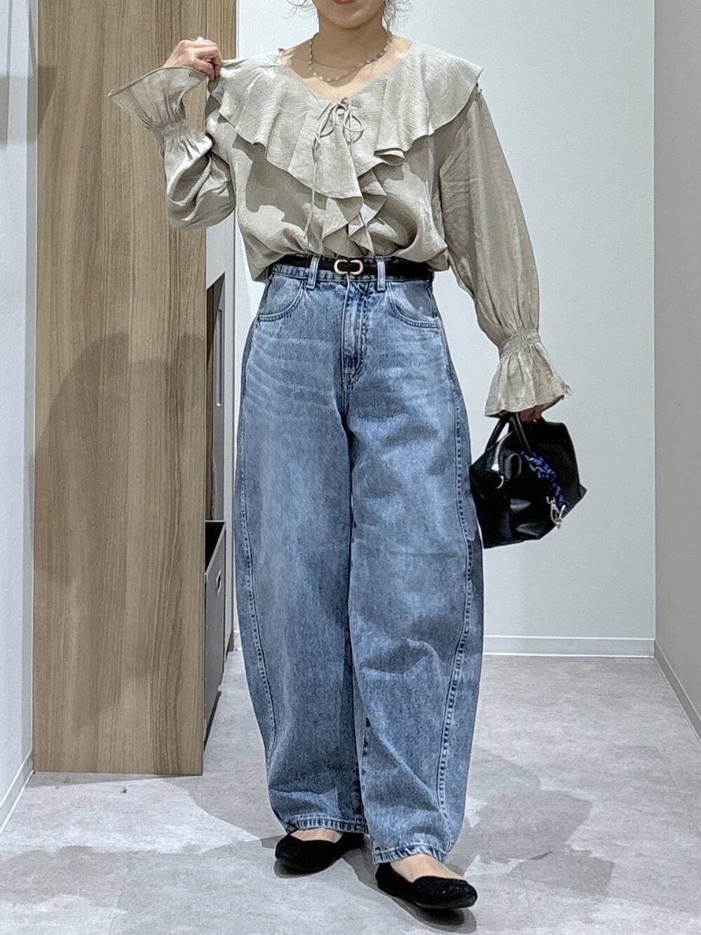 ブルー系のデニムパンツ、ブラック系のパンプス、ブラック系のボストンバッグを着用したレディースの春コーディネートの6枚目の写真
