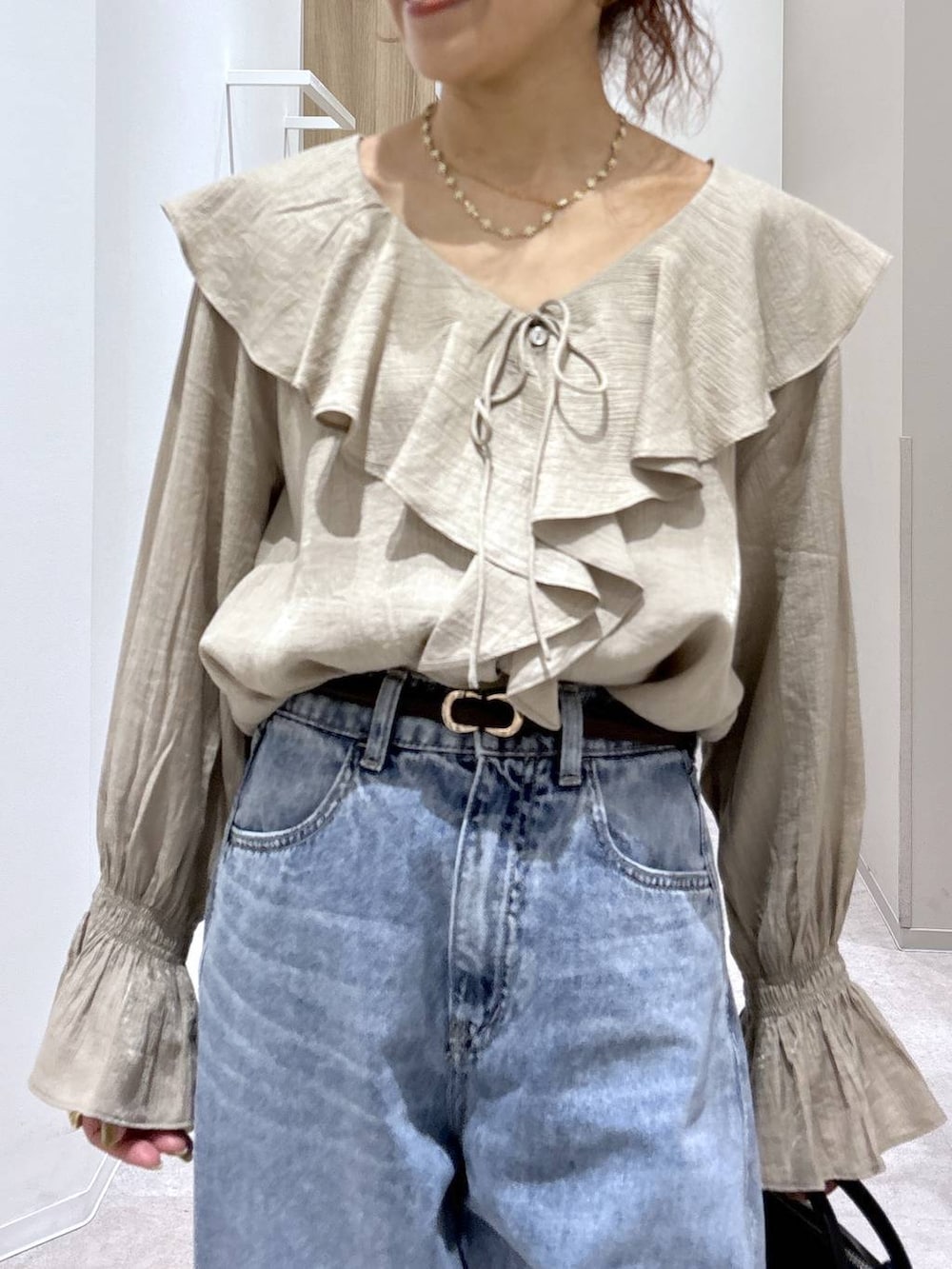 ブルー系のデニムパンツ、ブラック系のパンプス、ブラック系のボストンバッグを着用したレディースの春コーディネートの7枚目の写真