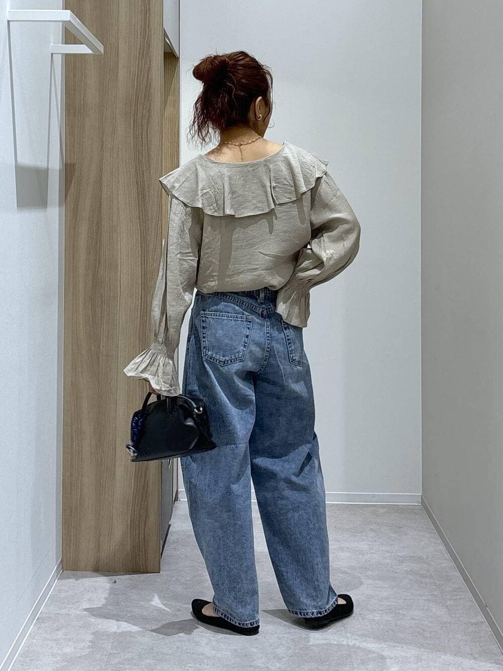 ブルー系のデニムパンツ、ブラック系のパンプス、ブラック系のボストンバッグを着用したレディースの春コーディネートの4枚目の写真