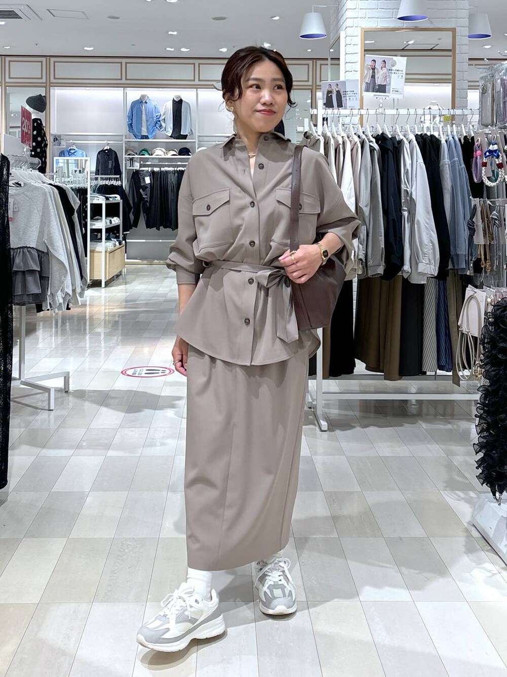 ブラウン系のショルダーバッグ、ブラウン系のスカート、ホワイト系のスニーカーを着用したレディースの春コーディネートの2枚目の写真