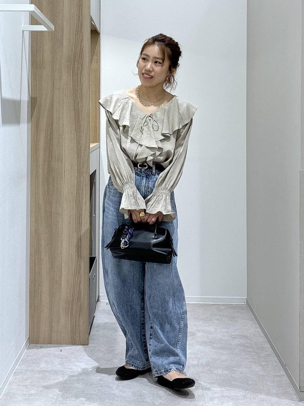 ブルー系のデニムパンツ、ブラック系のパンプス、ブラック系のボストンバッグを着用したレディースの春コーディネートの2枚目の写真