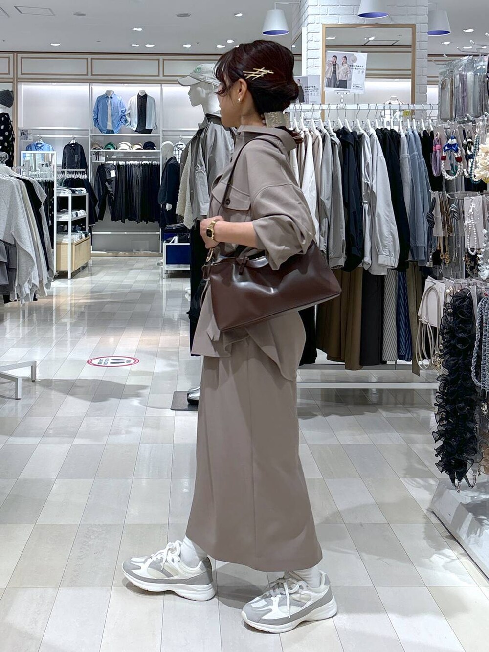 ブラウン系のショルダーバッグ、ブラウン系のスカート、ホワイト系のスニーカーを着用したレディースの春コーディネートの3枚目の写真