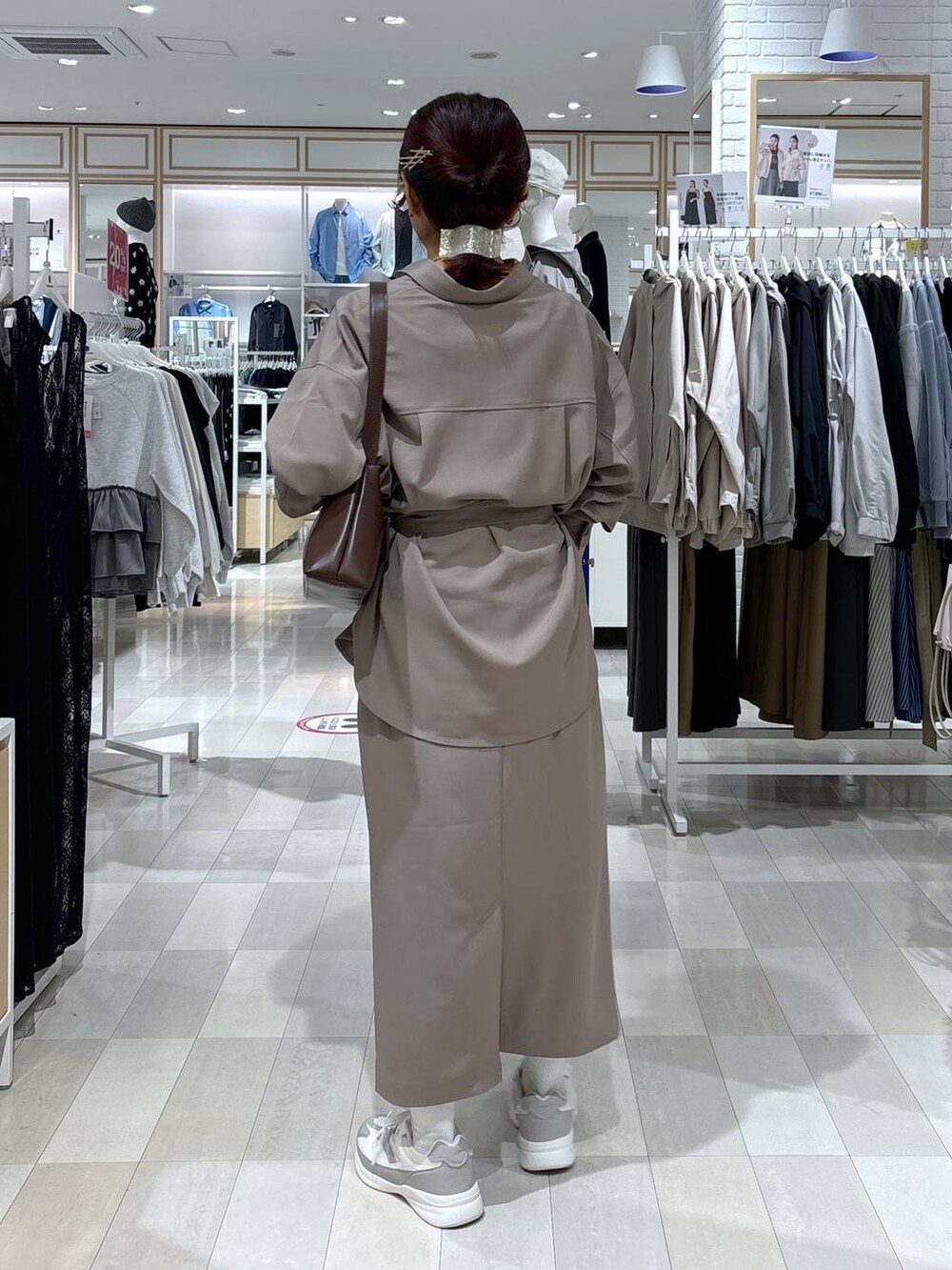 ブラウン系のショルダーバッグ、ブラウン系のスカート、ホワイト系のスニーカーを着用したレディースの春コーディネートの4枚目の写真