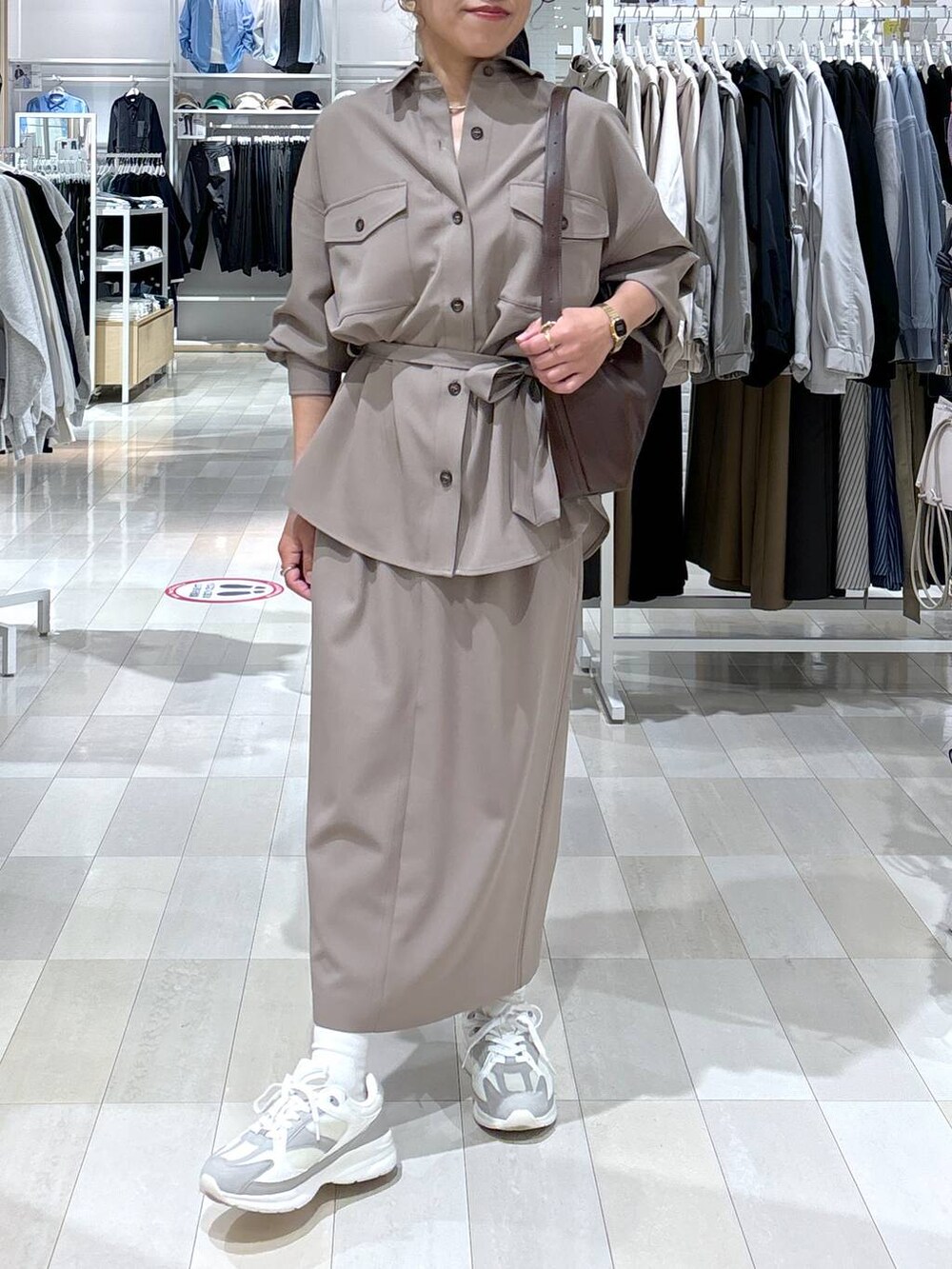 ブラウン系のショルダーバッグ、ブラウン系のスカート、ホワイト系のスニーカーを着用したレディースの春コーディネートの6枚目の写真