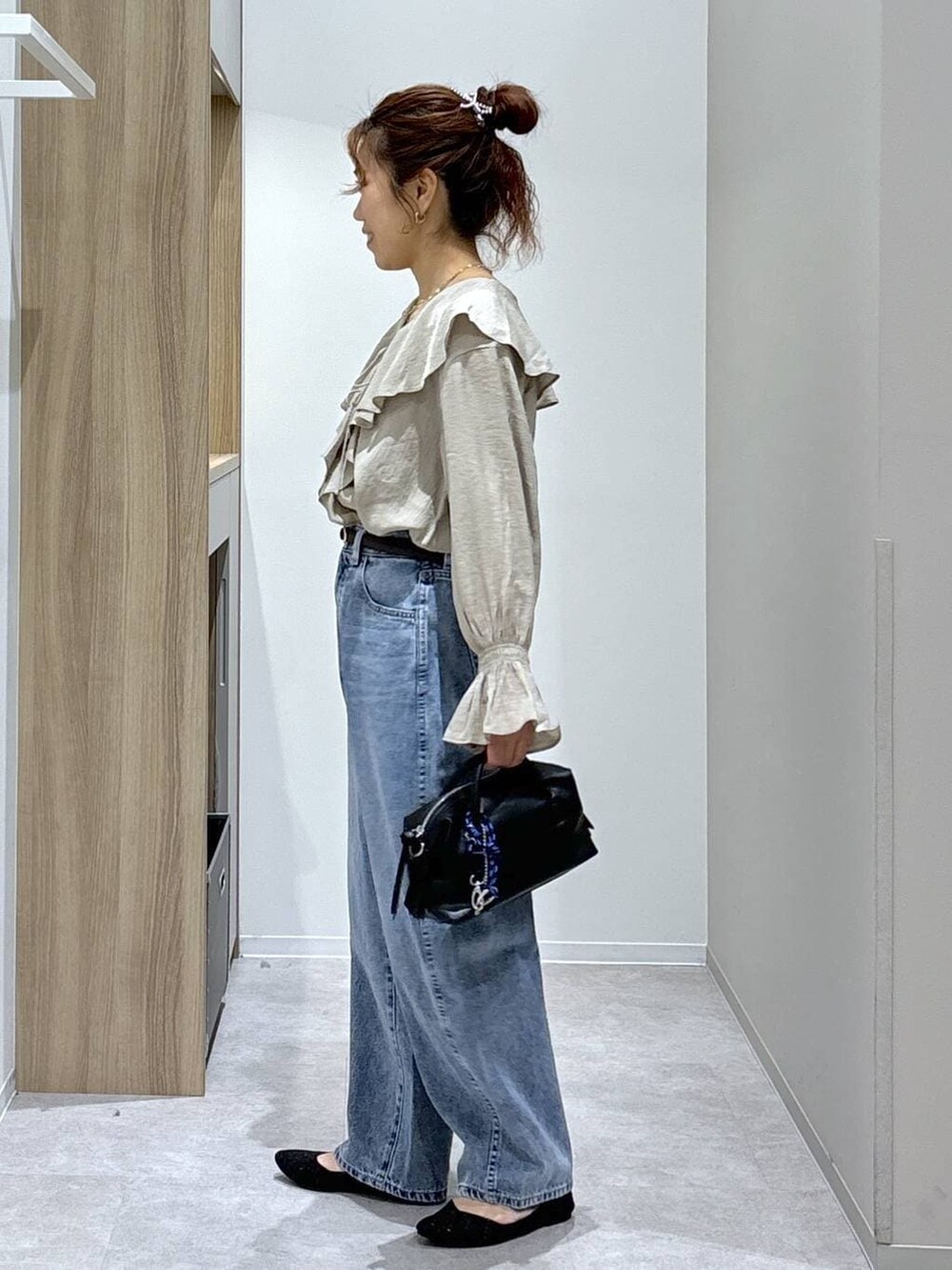ブルー系のデニムパンツ、ブラック系のパンプス、ブラック系のボストンバッグを着用したレディースの春コーディネートの5枚目の写真