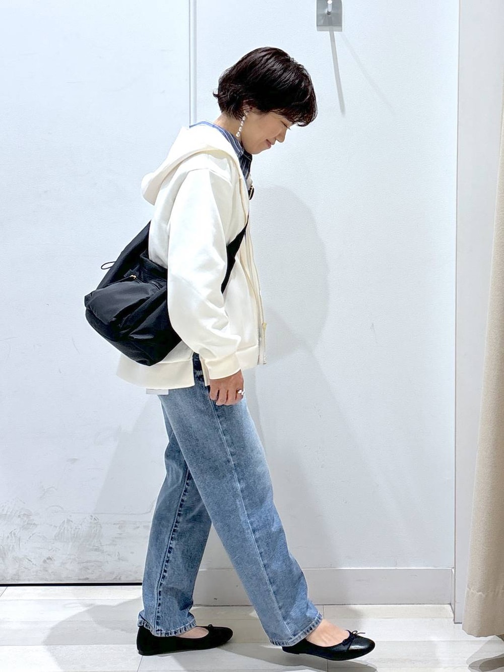 ブラック系のショルダーバッグ、ブルー系のデニムパンツ、その他のバレエシューズを着用したレディースの春コーディネートの4枚目の写真