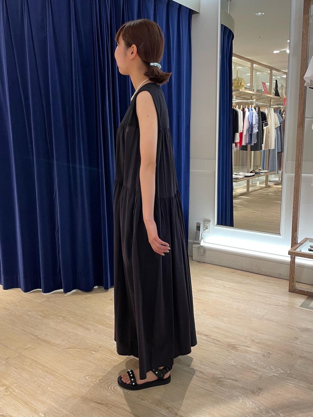 ブラック系のサンダル、ブラック系のワンピース、ホワイト系のネックレスを着用したレディースの夏コーディネートの5枚目の写真