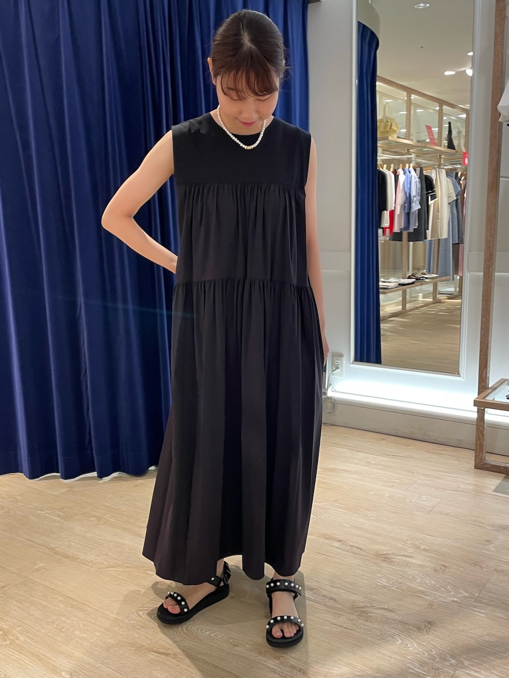 ブラック系のサンダル、ブラック系のワンピース、ホワイト系のネックレスを着用したレディースの夏コーディネートの2枚目の写真