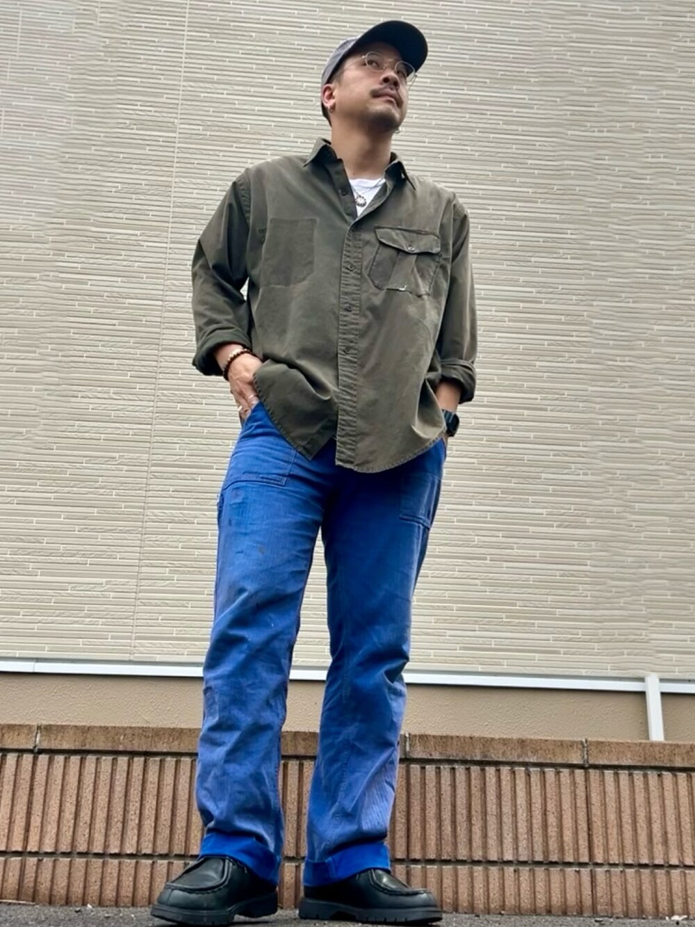 ブラック系のドレスシューズ、ブルー系のキャップを着用したメンズの春コーディネートの3枚目の写真