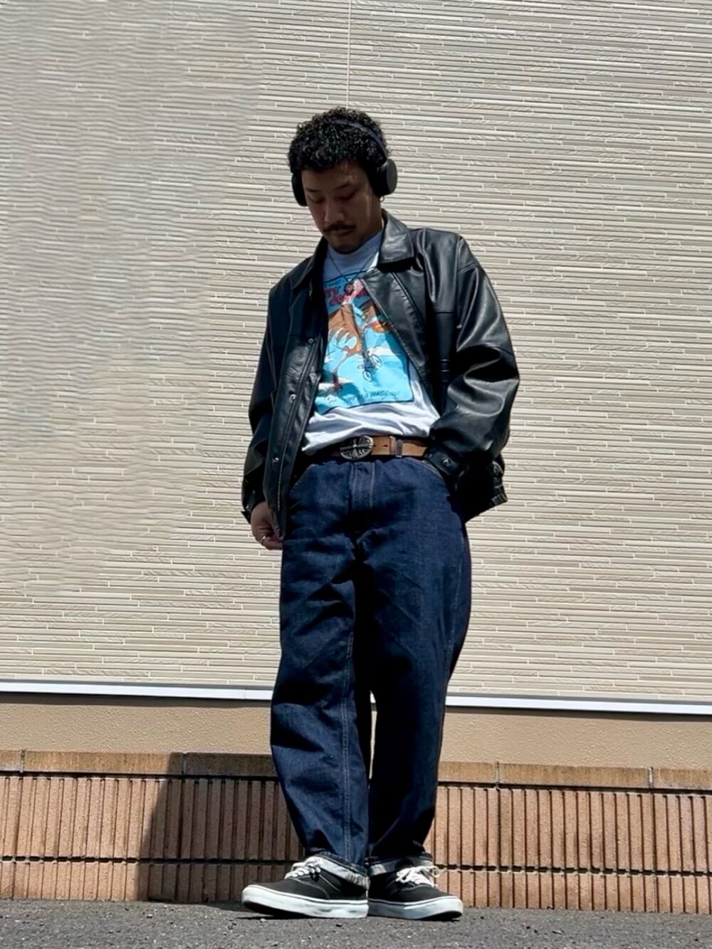 ブラック系のブルゾン、ブルー系のデニムパンツ、ブラック系のスニーカーを着用したメンズの春コーディネートの2枚目の写真