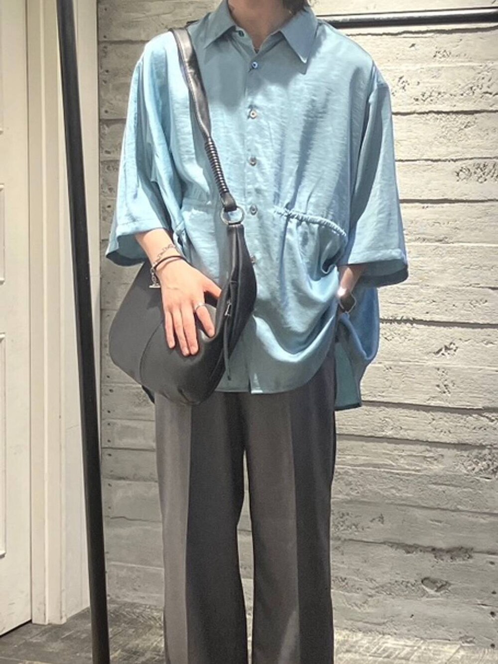 ブラック系のスニーカー、グレー系のスラックス、ブラック系のショルダーバッグを着用したメンズの夏コーディネートの2枚目の写真