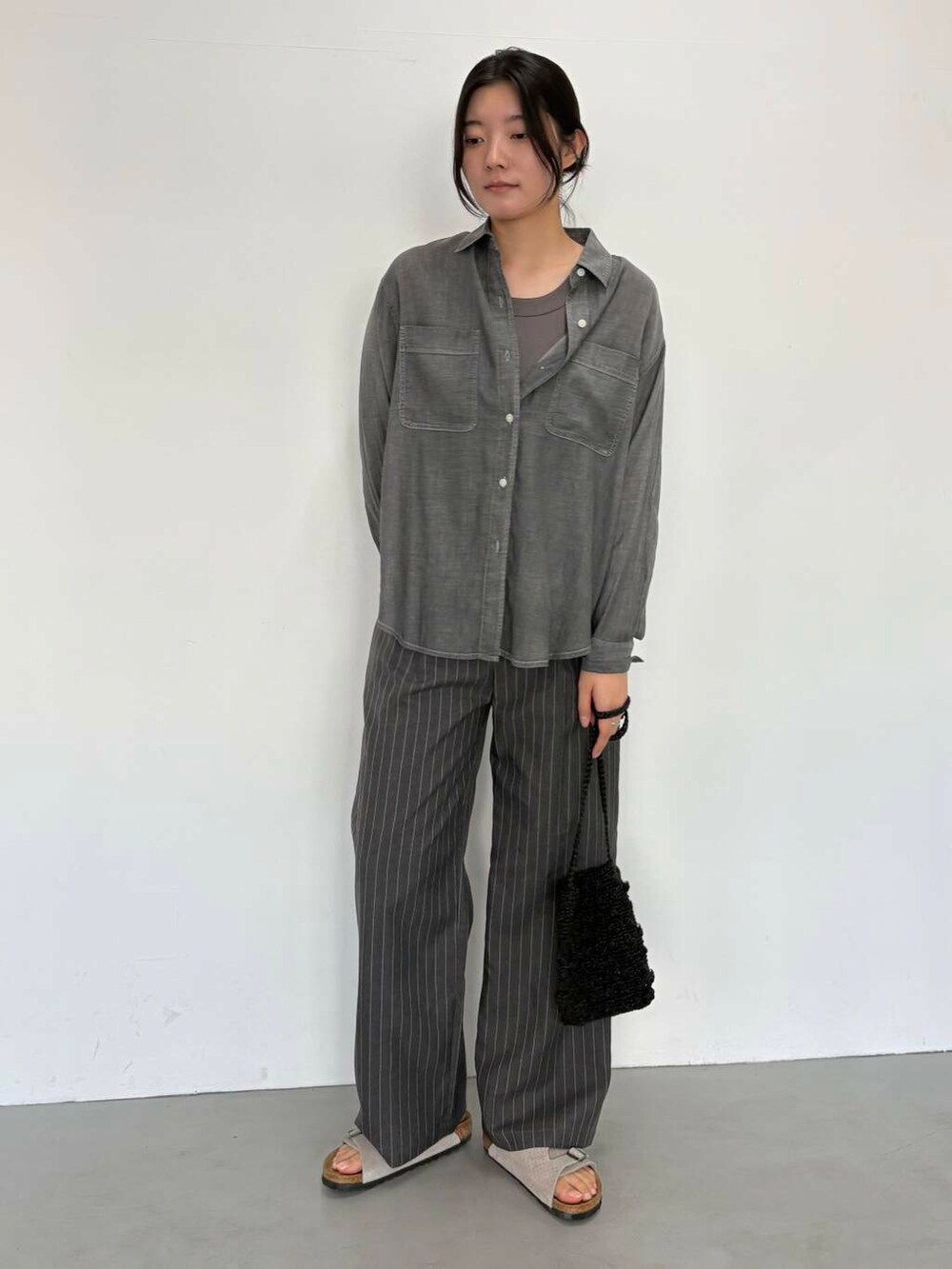 ブラック系のショルダーバッグ、グレー系のその他パンツ、ブラック系のシャツ/ブラウスを着用したレディースの夏コーディネートの2枚目の写真