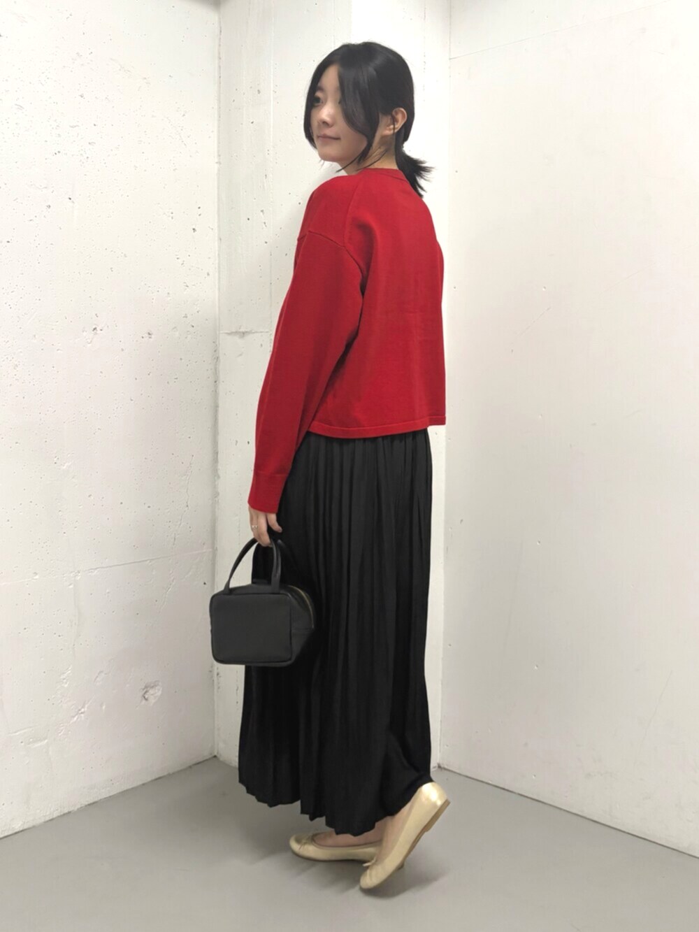 レッド系のカーディガン/ボレロ、ブラック系のスカートを着用したレディースの秋コーディネートの4枚目の写真