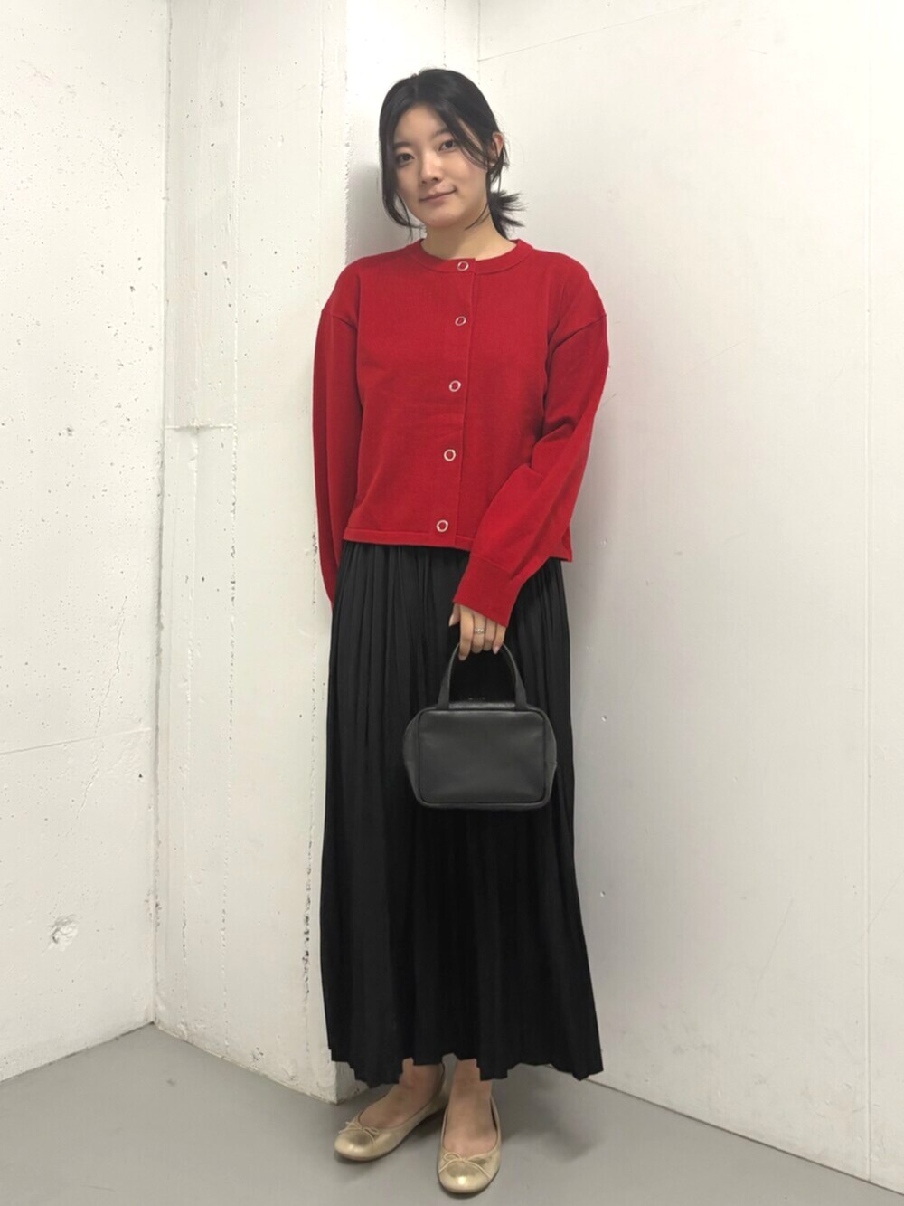 レッド系のカーディガン/ボレロ、ブラック系のスカートを着用したレディースの秋コーディネートの2枚目の写真