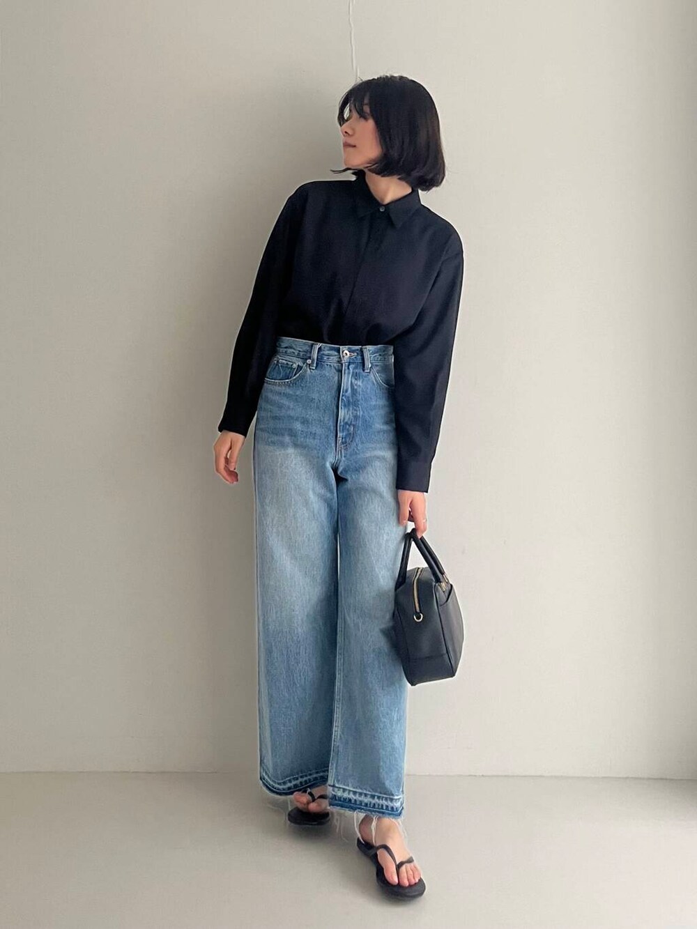 ブルー系のデニムパンツ、ブラック系のシャツ/ブラウス、ブラック系のハンドバッグを着用したレディースの夏コーディネートの2枚目の写真