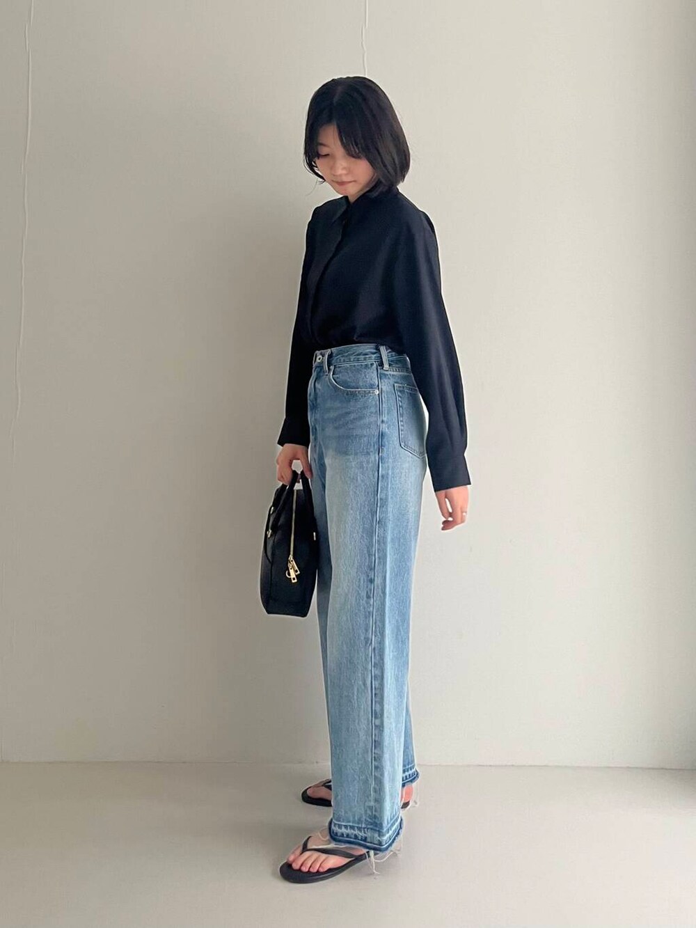 ブルー系のデニムパンツ、ブラック系のシャツ/ブラウス、ブラック系のハンドバッグを着用したレディースの夏コーディネートの5枚目の写真