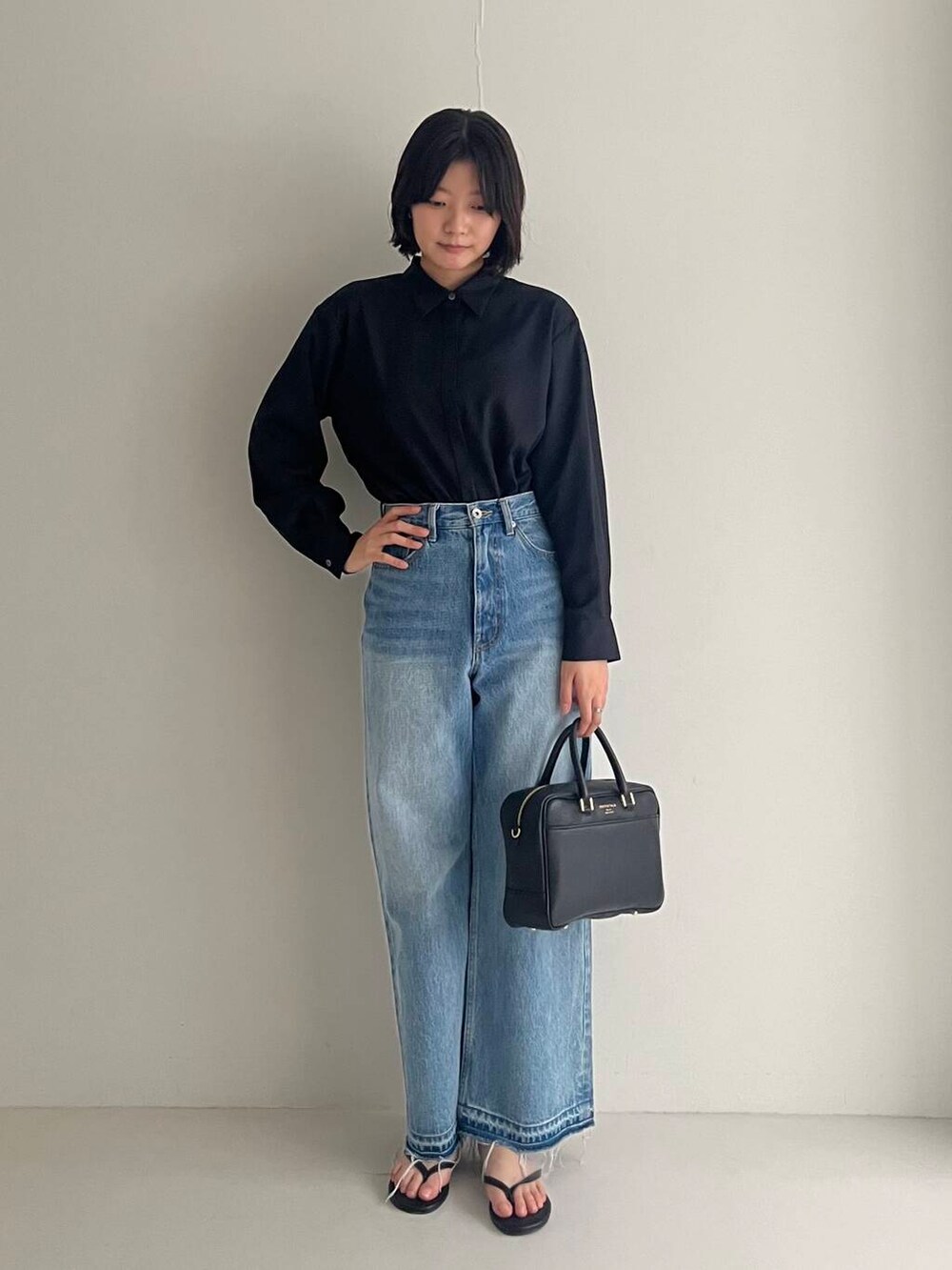ブルー系のデニムパンツ、ブラック系のシャツ/ブラウス、ブラック系のハンドバッグを着用したレディースの夏コーディネートの3枚目の写真