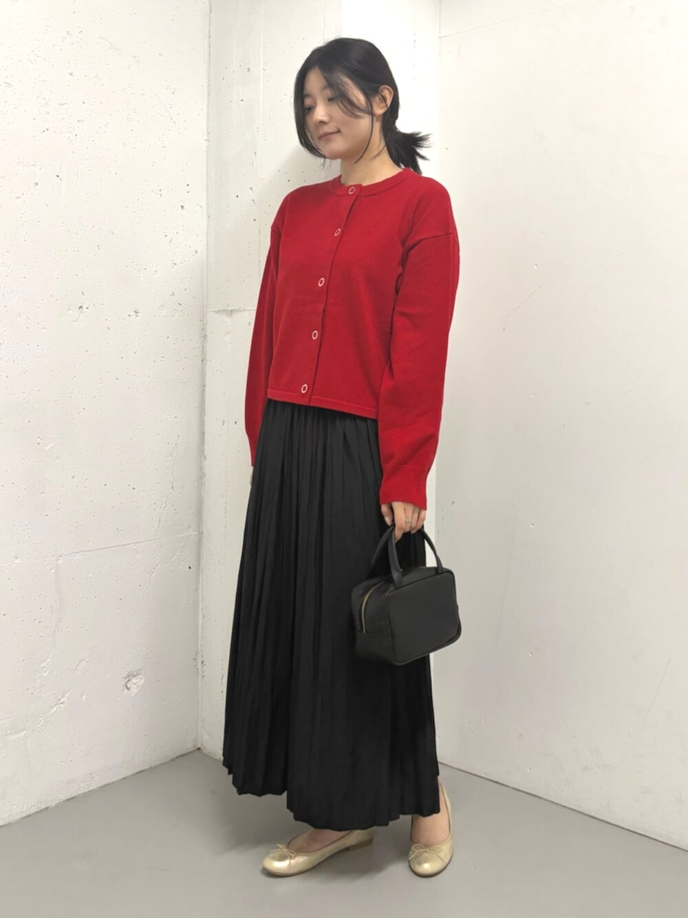 レッド系のカーディガン/ボレロ、ブラック系のスカートを着用したレディースの秋コーディネートの3枚目の写真