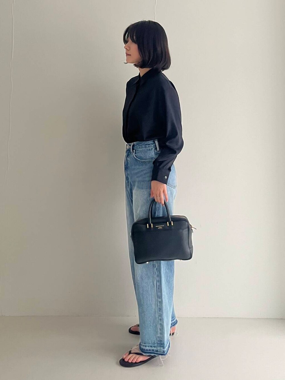 ブルー系のデニムパンツ、ブラック系のシャツ/ブラウス、ブラック系のハンドバッグを着用したレディースの夏コーディネートの4枚目の写真