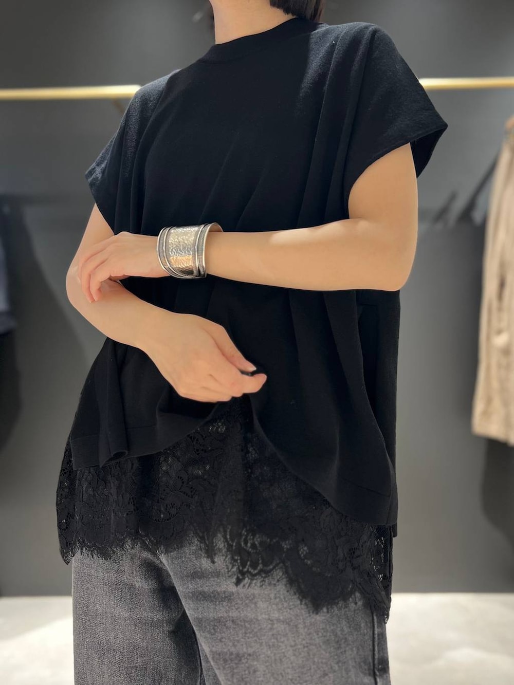 ブラック系のデニムパンツ、ブラック系のニット/セーター、シルバー系のバングル/リストバンドを着用したレディースの春コーディネートの4枚目の写真