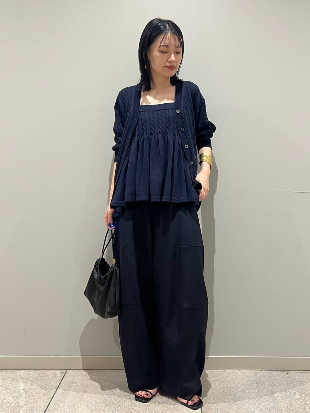 ブルー系のカーディガン/ボレロ、ブルー系のキャミソール、ブラック系のクラッチバッグを着用したレディースの秋コーディネートの2枚目の写真