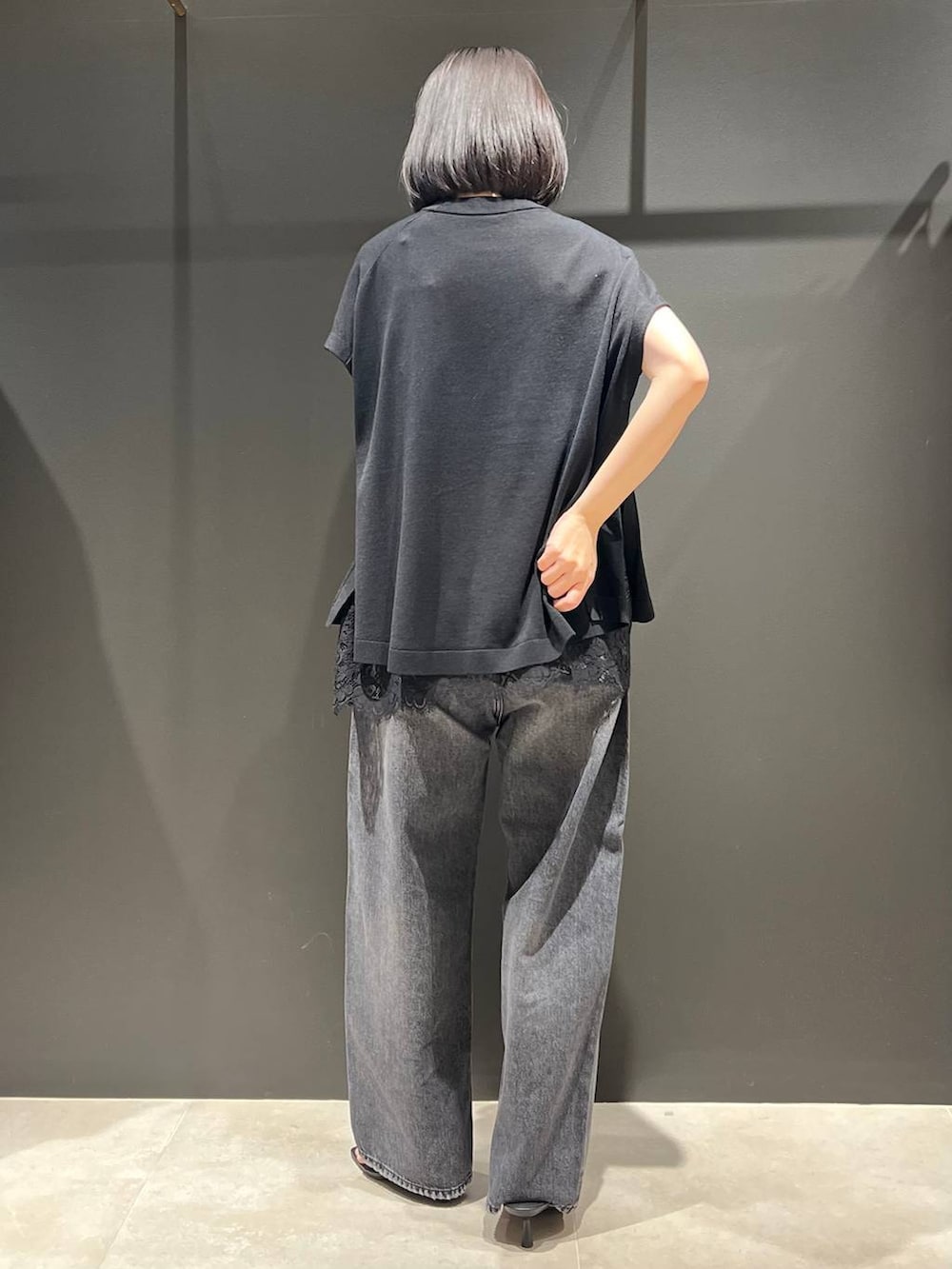 ブラック系のデニムパンツ、ブラック系のニット/セーター、シルバー系のバングル/リストバンドを着用したレディースの春コーディネートの3枚目の写真