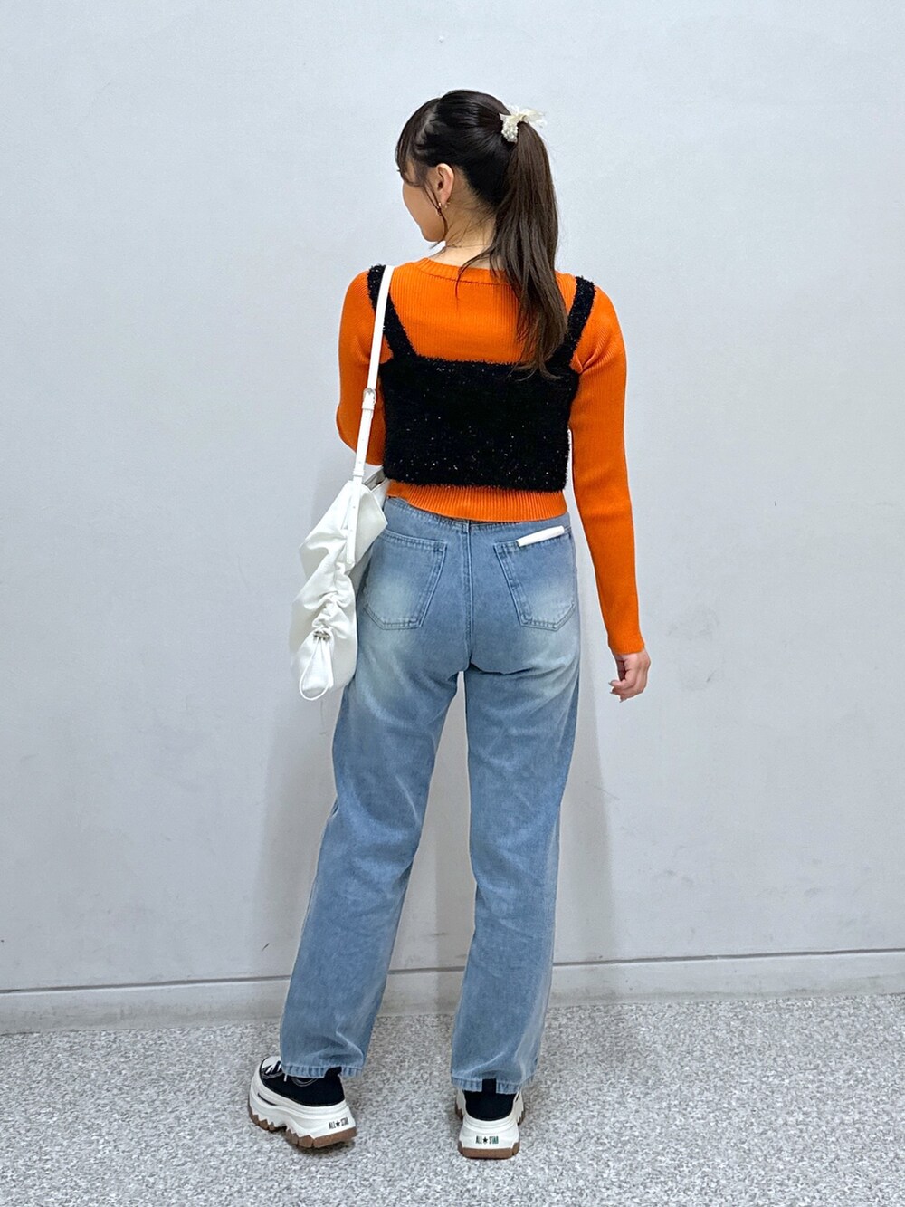 ブルー系のデニムパンツ、ホワイト系のトートバッグ、オレンジ系のニット/セーターを着用したレディースの秋コーディネートの4枚目の写真