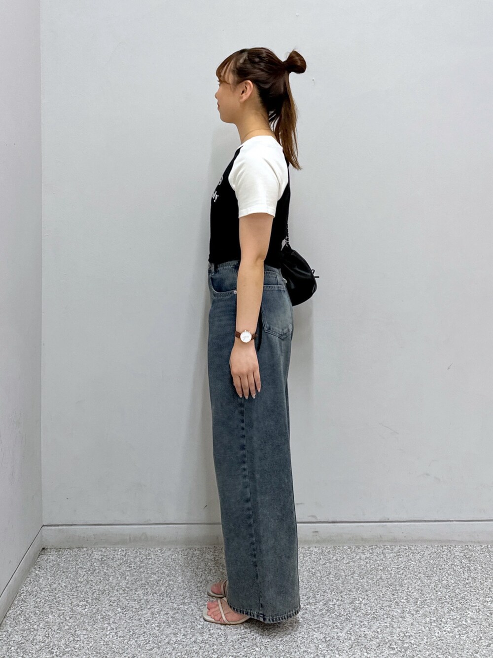 ブルー系のデニムパンツ、ブラック系のTシャツ/カットソー、ブラック系のショルダーバッグを着用したレディースの夏コーディネートの3枚目の写真