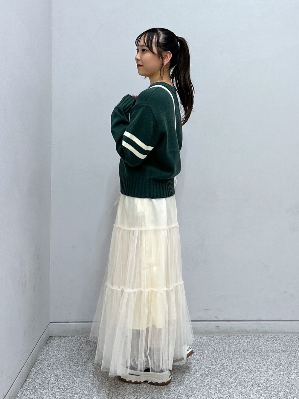 グリーン系のニット/セーター、ホワイト系のスカート、ホワイト系のトートバッグを着用したレディースの秋コーディネートの2枚目の写真