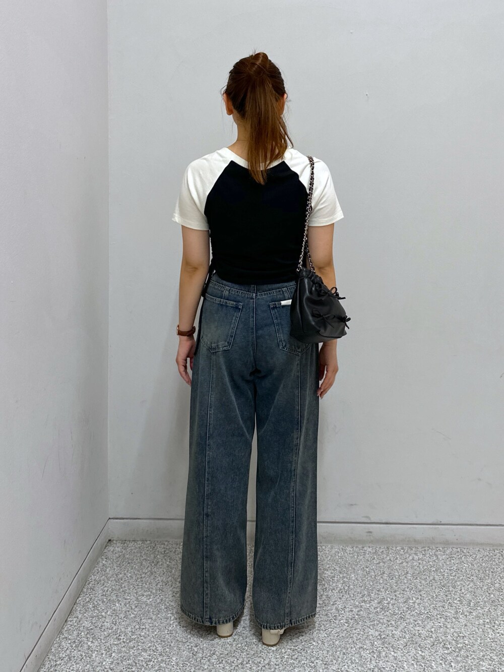 ブルー系のデニムパンツ、ブラック系のTシャツ/カットソー、ブラック系のショルダーバッグを着用したレディースの夏コーディネートの4枚目の写真