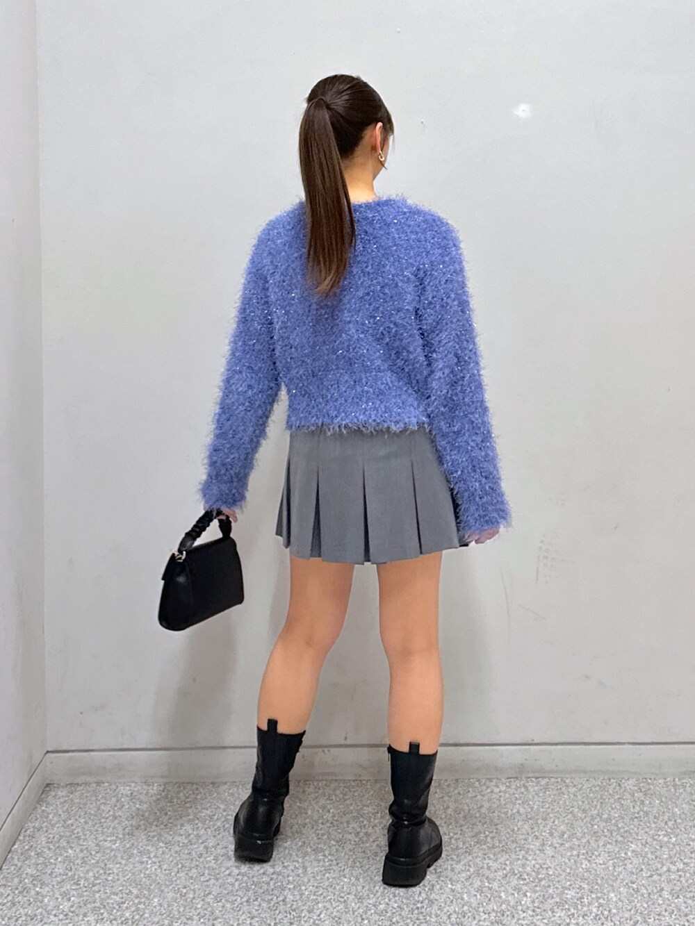 グレー系のスカート、ブルー系のニット/セーター、ブラック系のショルダーバッグを着用したレディースの冬コーディネートの3枚目の写真