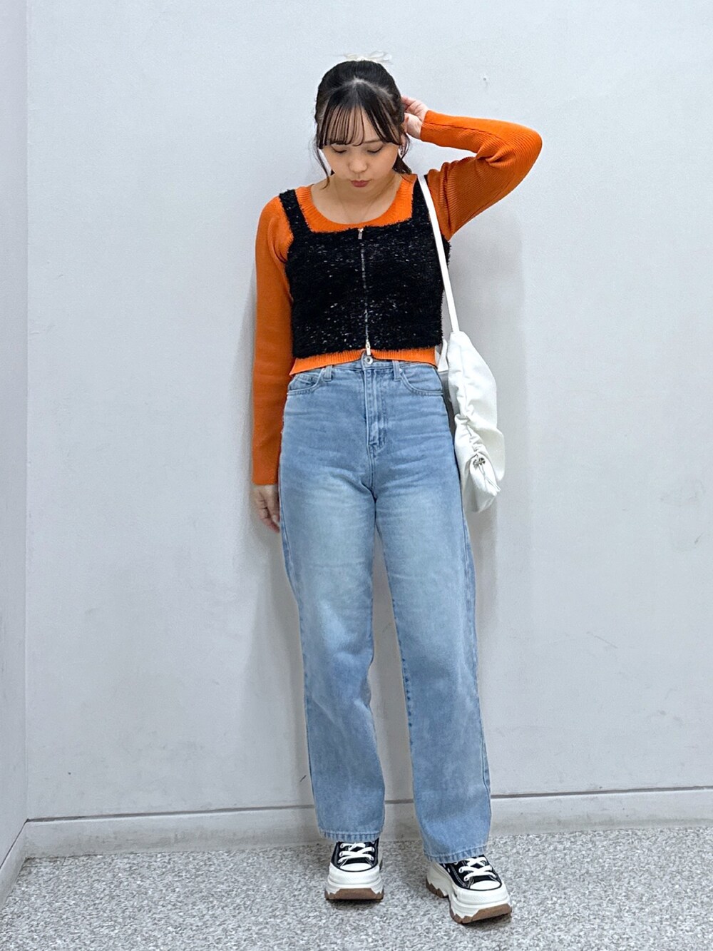 ブルー系のデニムパンツ、ホワイト系のトートバッグ、オレンジ系のニット/セーターを着用したレディースの秋コーディネートの2枚目の写真