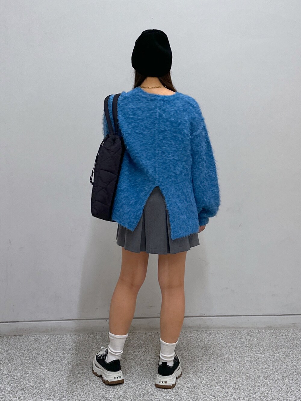 グレー系のスカート、ブラック系のトートバッグ、グリーン系のニット/セーターを着用したレディースの冬コーディネートの4枚目の写真