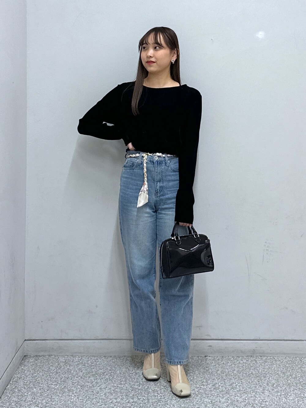ブルー系のデニムパンツ、ブラック系のTシャツ/カットソー、ブラック系のショルダーバッグを着用したレディースの冬コーディネートの2枚目の写真