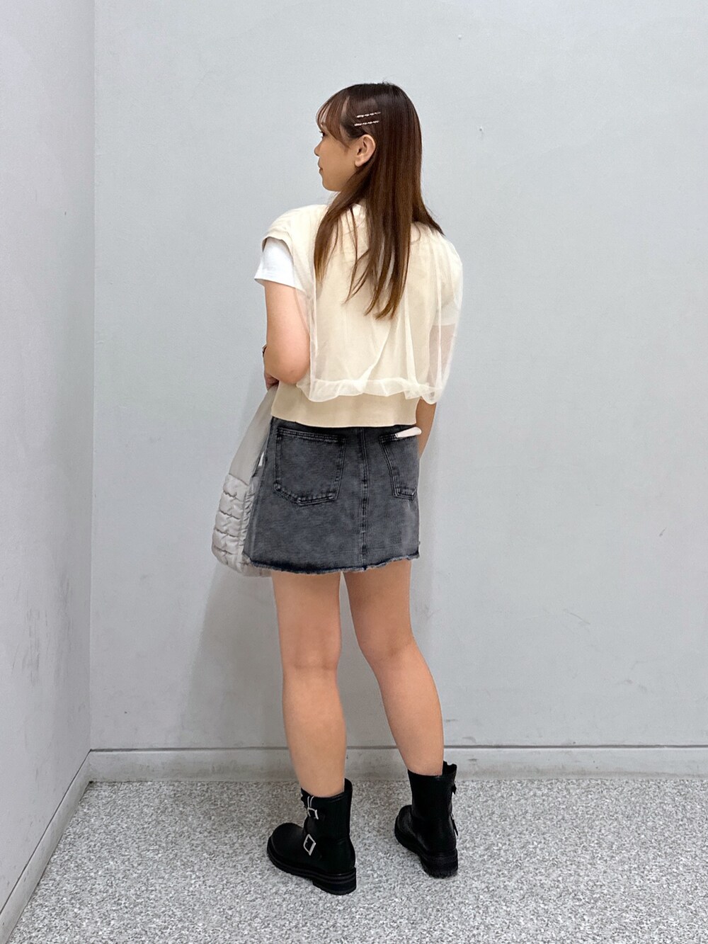 ブラック系のスカート、ブラック系のブーツ、ホワイト系のハンドバッグを着用したレディースの夏コーディネートの2枚目の写真