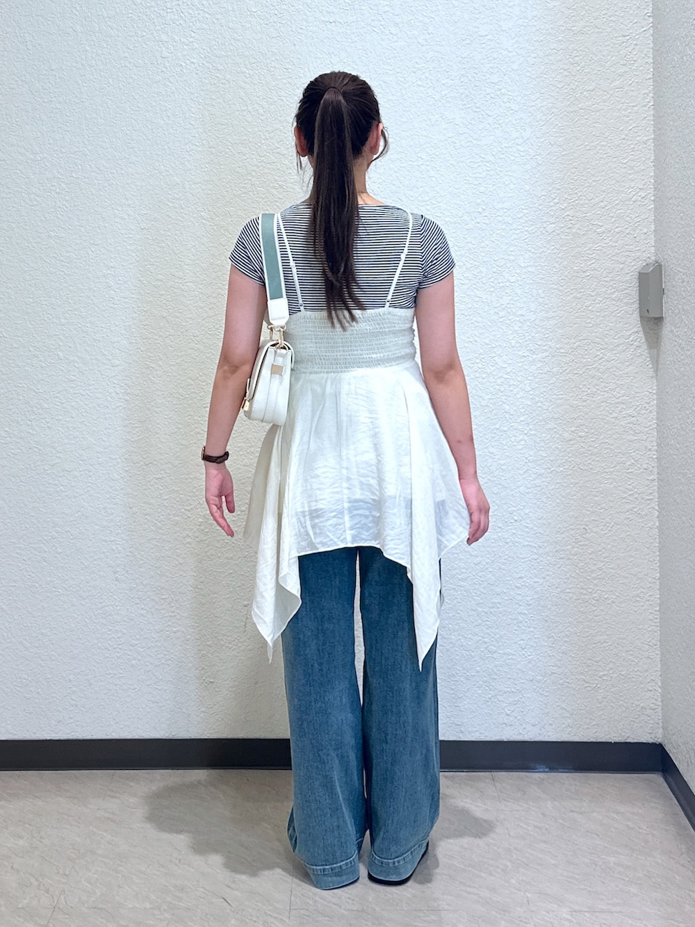 ホワイト系のワンピース、ブルー系のデニムパンツ、ブラック系のサンダルを着用したレディースの夏コーディネートの5枚目の写真