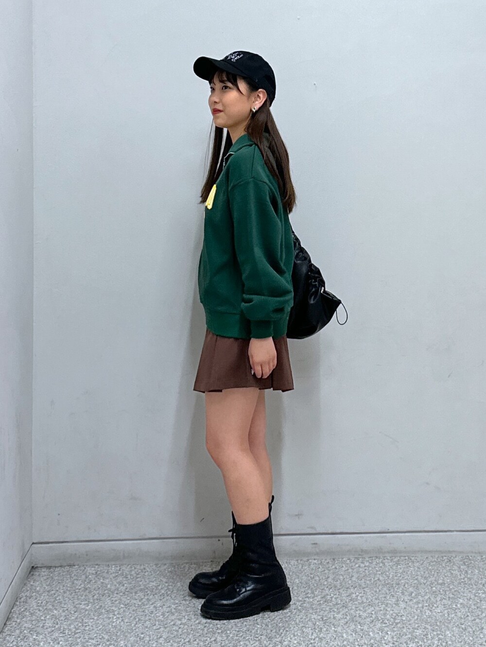 ブラウン系のスカート、グリーン系のスウェット、ブラック系のトートバッグを着用したレディースの冬コーディネートの2枚目の写真