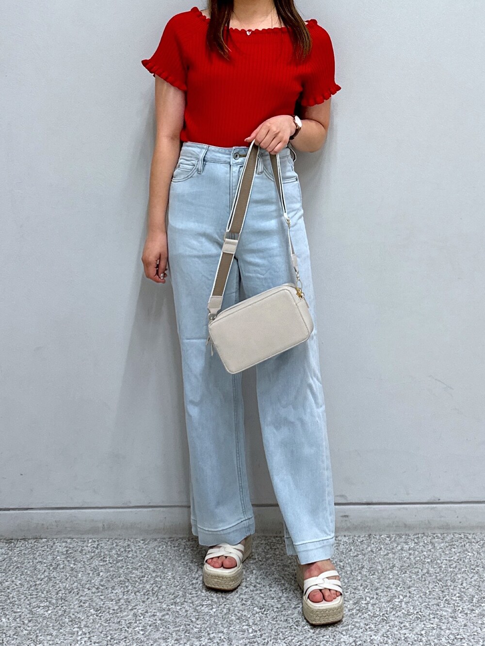 レッド系のニット/セーター、ホワイト系のショルダーバッグ、ブルー系のデニムパンツを着用したレディースの夏コーディネートの4枚目の写真