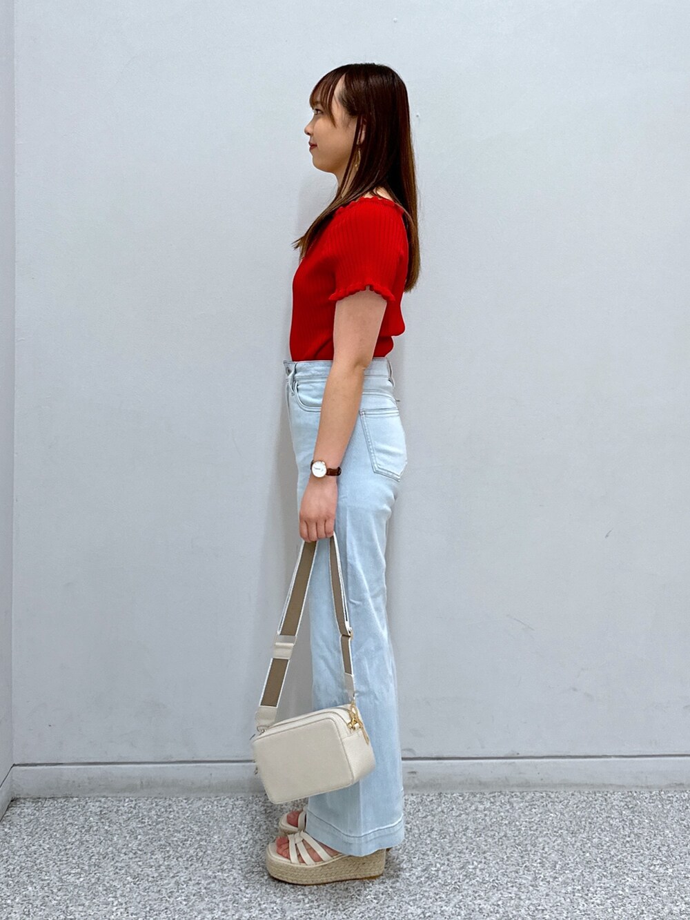 レッド系のニット/セーター、ホワイト系のショルダーバッグ、ブルー系のデニムパンツを着用したレディースの夏コーディネートの3枚目の写真