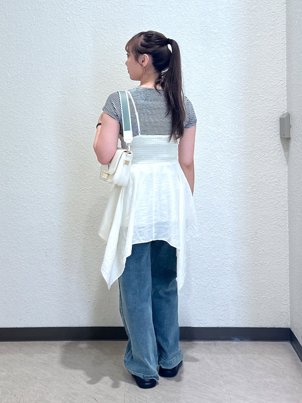 ホワイト系のワンピース、ブルー系のデニムパンツ、ブラック系のサンダルを着用したレディースの夏コーディネートの4枚目の写真