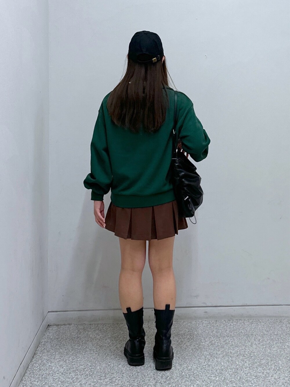 ブラウン系のスカート、グリーン系のスウェット、ブラック系のトートバッグを着用したレディースの冬コーディネートの3枚目の写真