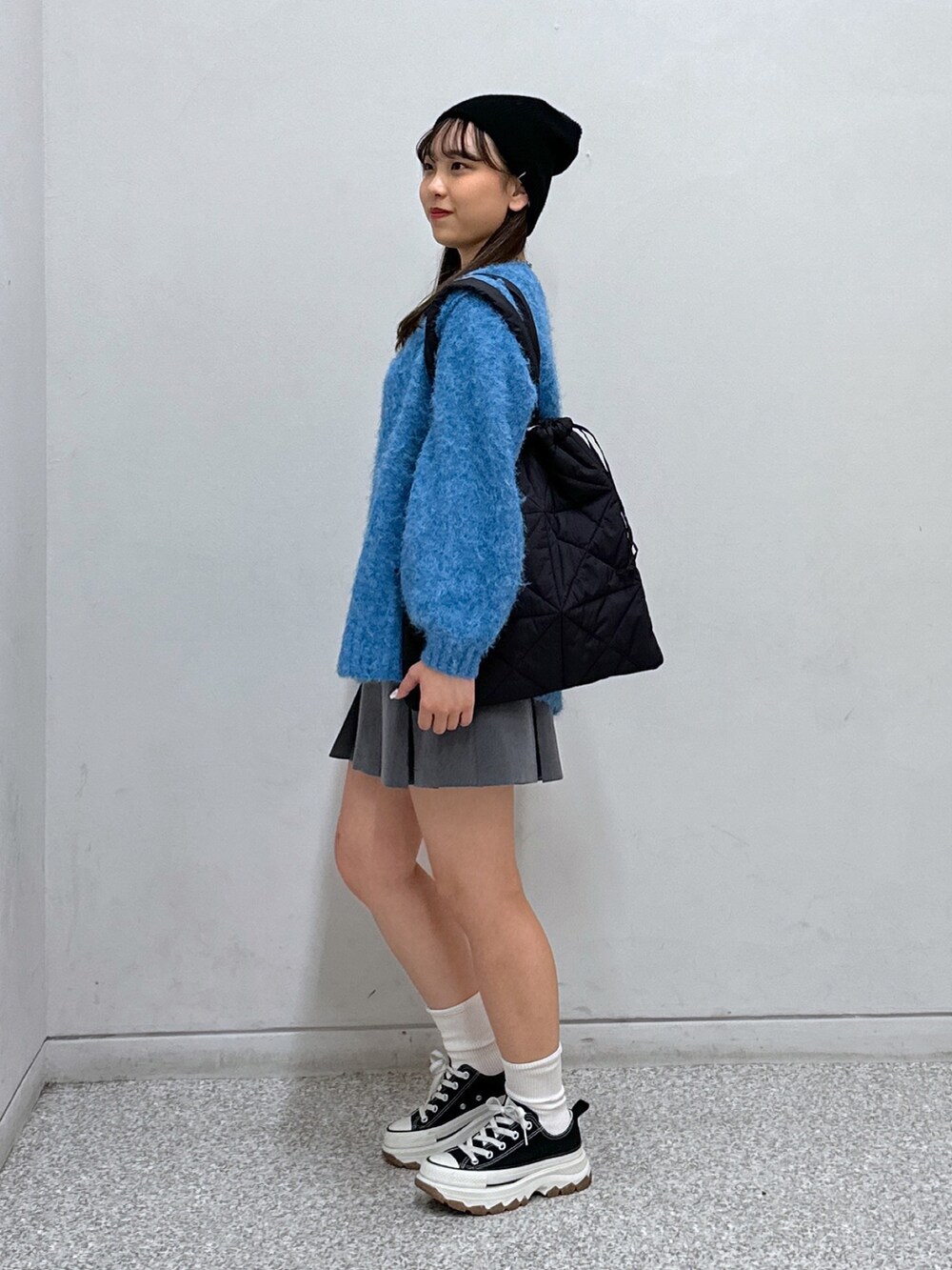 グレー系のスカート、ブラック系のトートバッグ、グリーン系のニット/セーターを着用したレディースの冬コーディネートの3枚目の写真