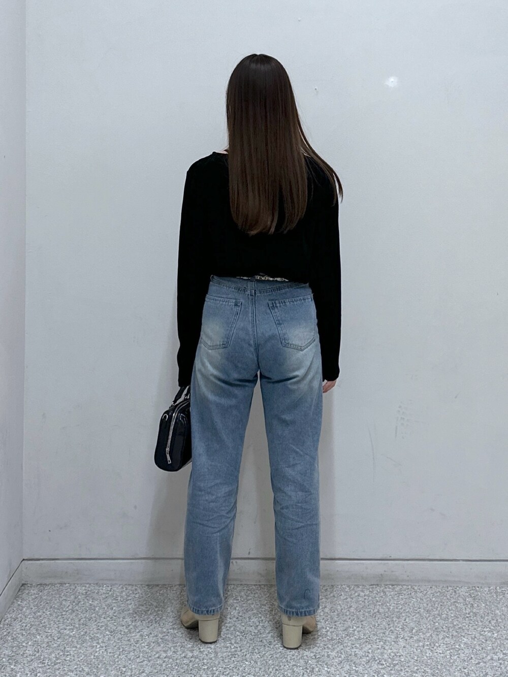 ブルー系のデニムパンツ、ブラック系のTシャツ/カットソー、ブラック系のショルダーバッグを着用したレディースの冬コーディネートの3枚目の写真
