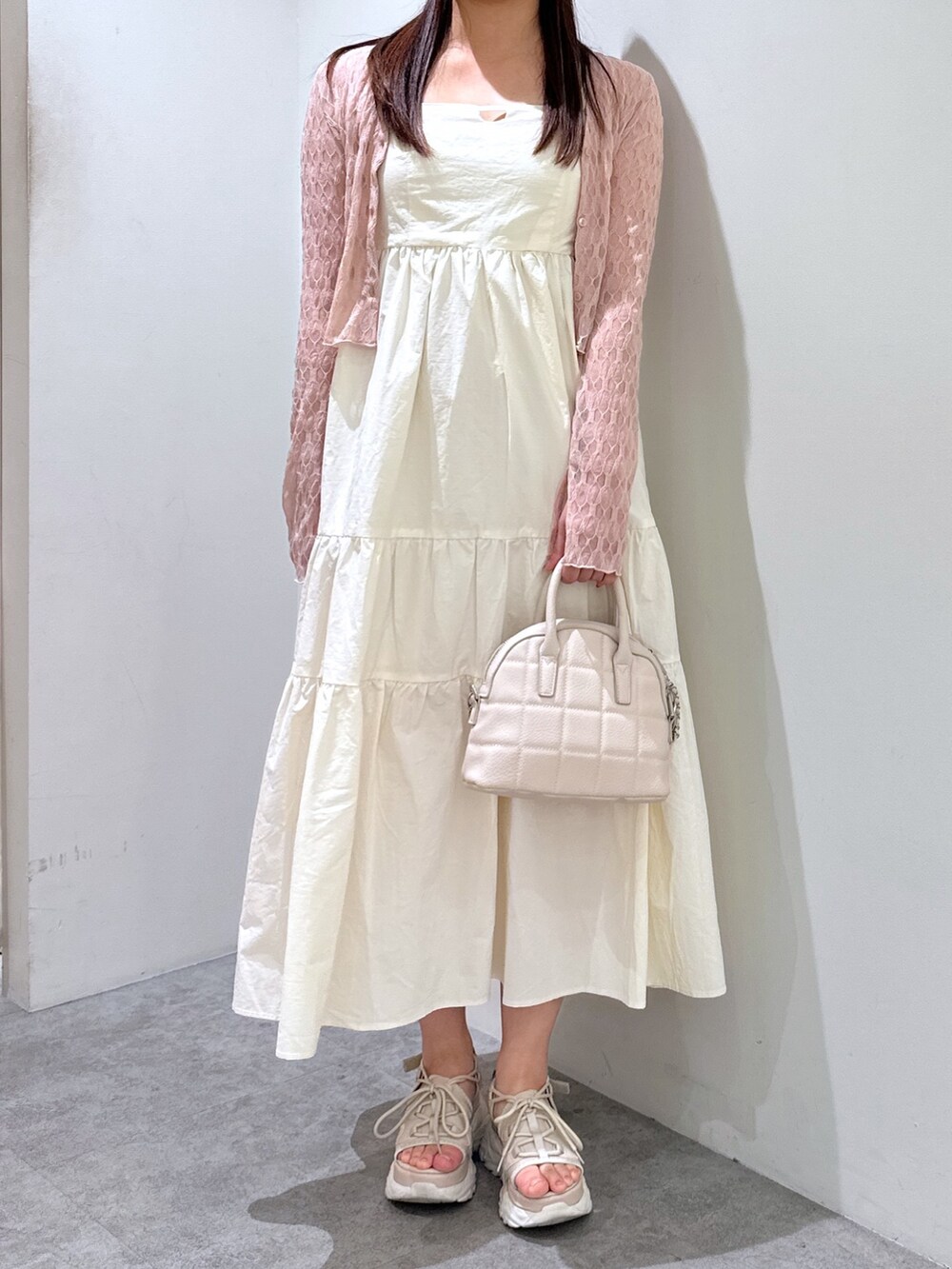 ホワイト系のワンピース、ピンク系のカーディガン/ボレロ、ホワイト系のショルダーバッグを着用したレディースの春コーディネートの3枚目の写真