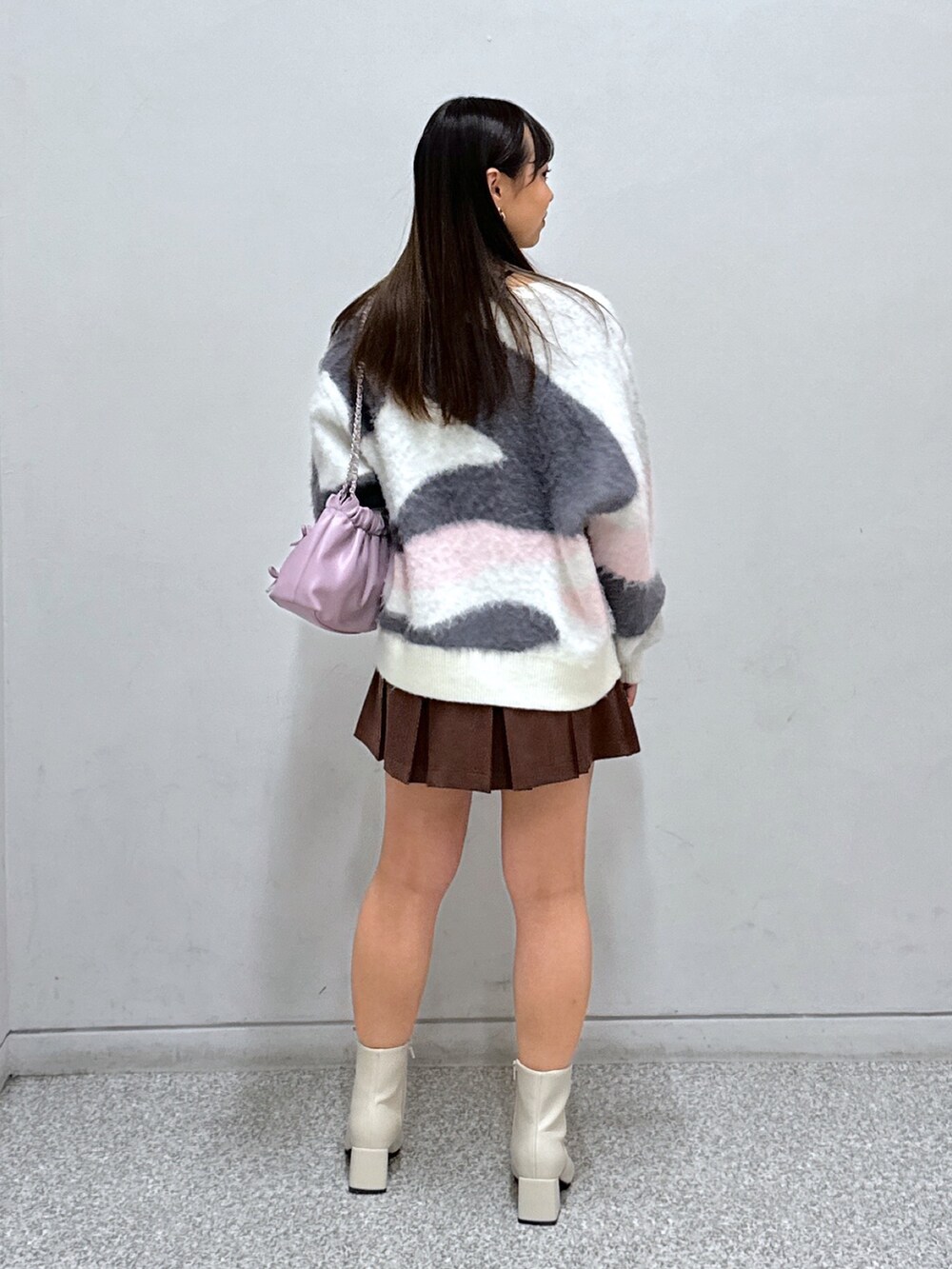 ホワイト系のニット/セーター、ブラウン系のスカート、ホワイト系のブーツを着用したレディースの冬コーディネートの3枚目の写真