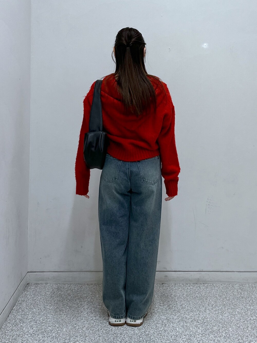 ブルー系のデニムパンツ、レッド系のニット/セーター、ブラック系のショルダーバッグを着用したレディースの冬コーディネートの2枚目の写真