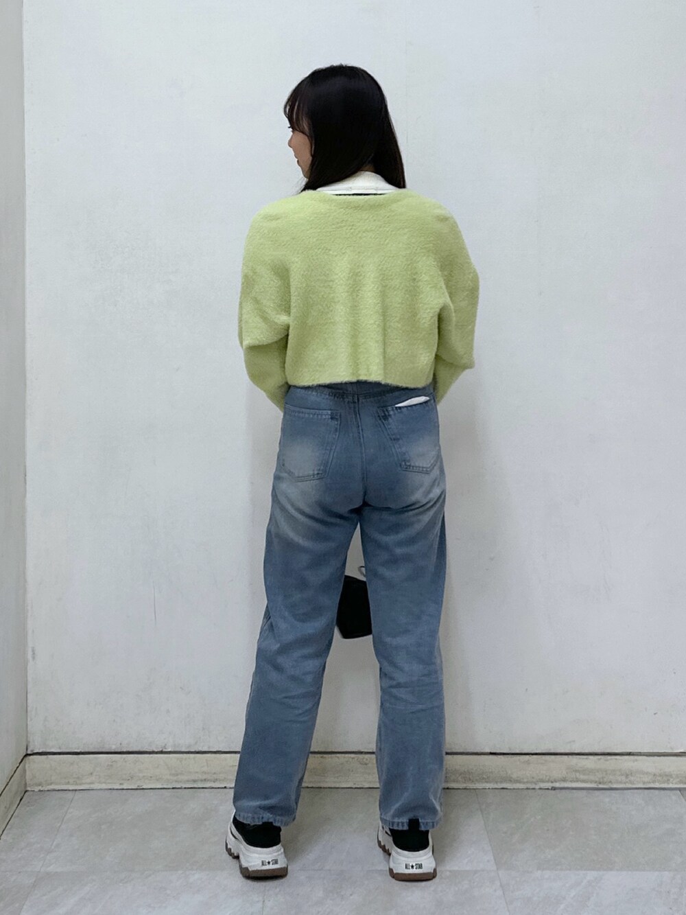 ホワイト系のニット/セーター、グリーン系のカーディガン/ボレロ、ブラック系のハンドバッグを着用したレディースの冬コーディネートの3枚目の写真